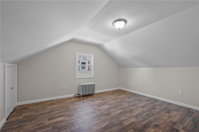 additional living space with dark wood-type flooring, radiator heating unit, and vaulted ceiling