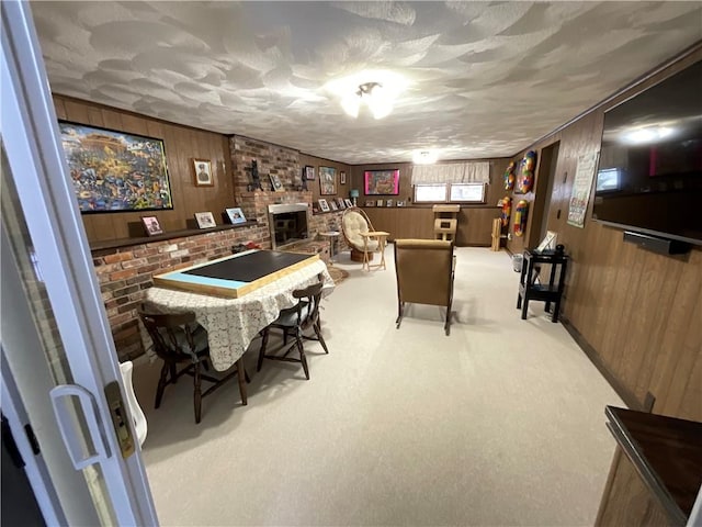 game room with light carpet, a fireplace, a textured ceiling, and wood walls