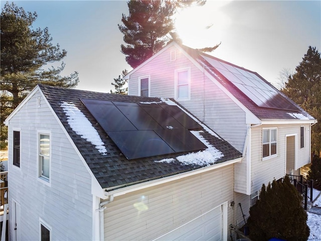 property exterior at dusk featuring a garage and solar panels