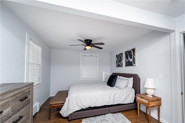 bedroom with dark hardwood / wood-style floors, ceiling fan, and baseboard heating