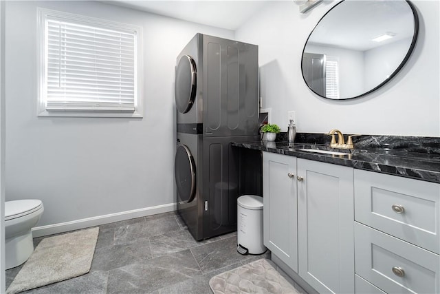 bathroom featuring vanity, stacked washer and clothes dryer, and toilet