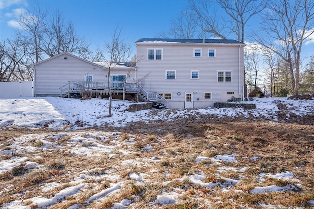 snow covered house featuring a wooden deck