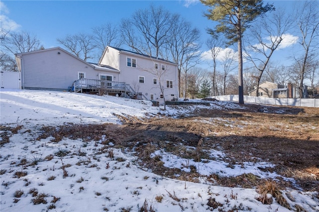 snow covered back of property with a wooden deck