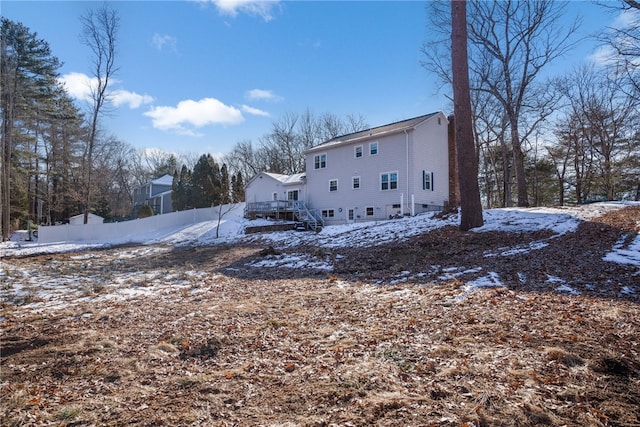 snow covered rear of property with a deck