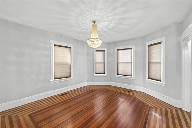 spare room featuring an inviting chandelier and hardwood / wood-style flooring