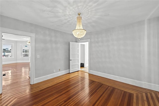 unfurnished room with an inviting chandelier and hardwood / wood-style flooring