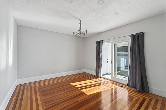 spare room with hardwood / wood-style flooring, plenty of natural light, a chandelier, and a textured ceiling