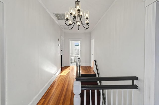 stairs featuring hardwood / wood-style floors, ornamental molding, and a chandelier