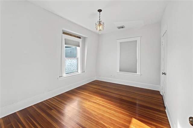 empty room with hardwood / wood-style flooring and a chandelier