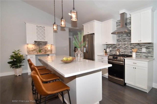 kitchen with white cabinets, appliances with stainless steel finishes, decorative backsplash, and wall chimney exhaust hood