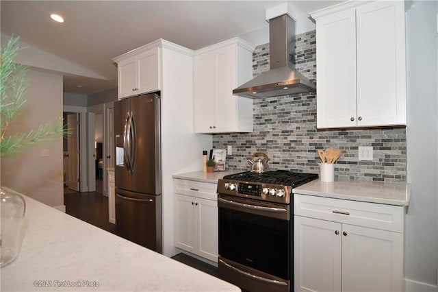 kitchen with stainless steel appliances, wall chimney range hood, white cabinets, and backsplash