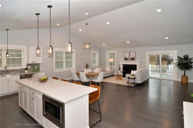 kitchen with stainless steel appliances, a center island, tasteful backsplash, white cabinets, and a kitchen bar