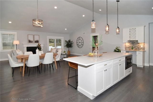 kitchen featuring hanging light fixtures, white cabinetry, a kitchen island, and lofted ceiling