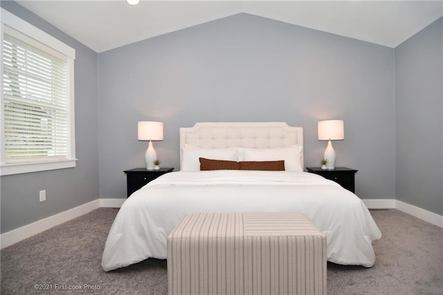 carpeted bedroom with lofted ceiling and multiple windows