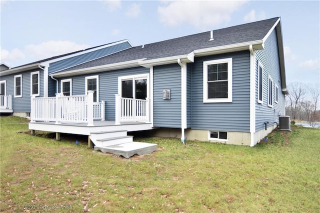 rear view of house featuring central AC unit, a deck, and a lawn