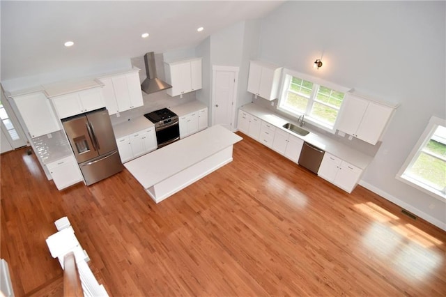 kitchen with white cabinetry, appliances with stainless steel finishes, a healthy amount of sunlight, and wall chimney range hood