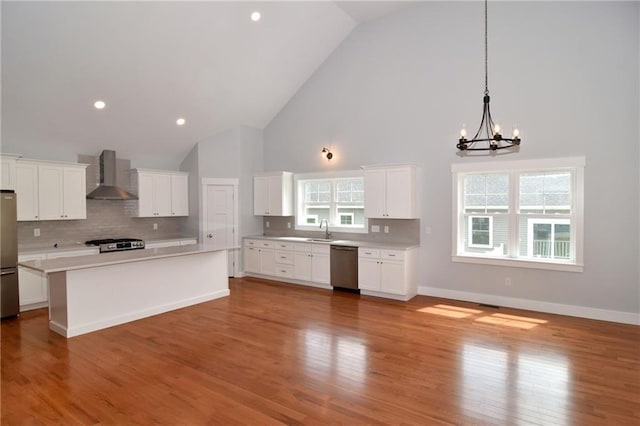 kitchen with stainless steel appliances, white cabinetry, tasteful backsplash, and wall chimney exhaust hood