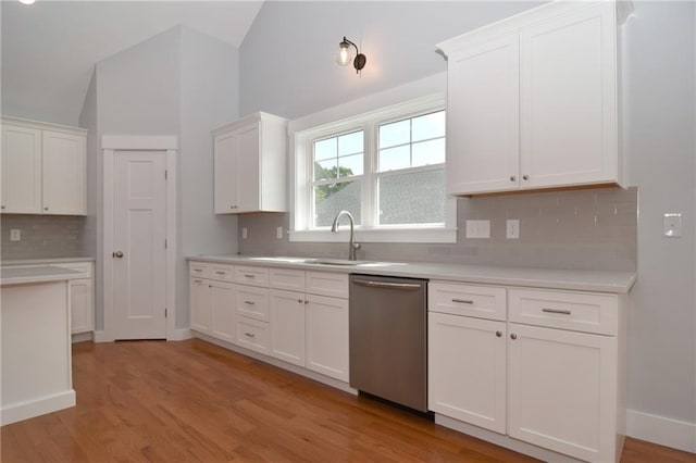 kitchen featuring lofted ceiling, stainless steel dishwasher, and white cabinets