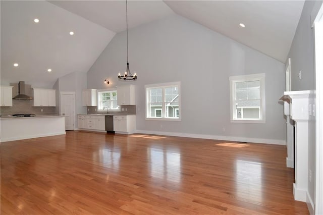 unfurnished living room featuring light wood-type flooring, a chandelier, and high vaulted ceiling