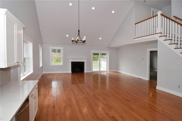 unfurnished living room with an inviting chandelier, a high ceiling, and light wood-type flooring