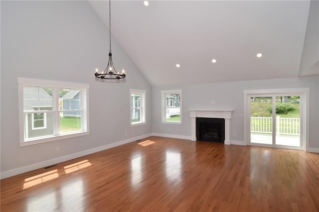 unfurnished living room with wood-type flooring, a notable chandelier, and high vaulted ceiling