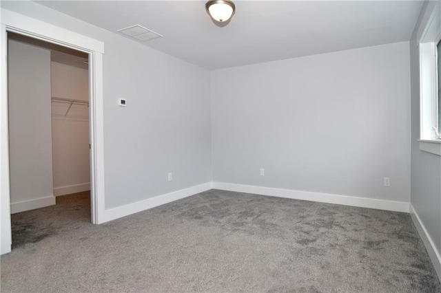 unfurnished bedroom with a spacious closet, a closet, and carpet flooring