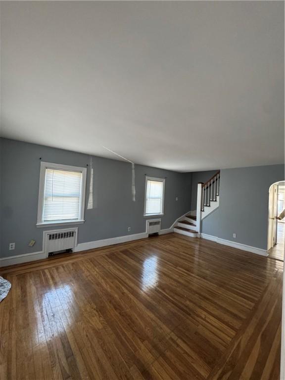 unfurnished living room with radiator heating unit and dark hardwood / wood-style floors