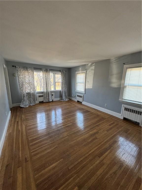 empty room with radiator heating unit and dark hardwood / wood-style floors