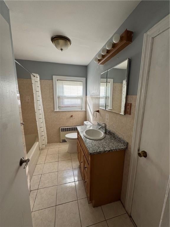 full bathroom with radiator heating unit, shower / tub combo with curtain, tile walls, vanity, and tile patterned floors