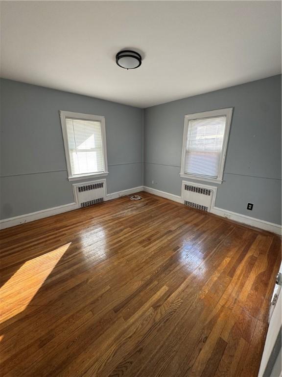 spare room with hardwood / wood-style floors and radiator heating unit