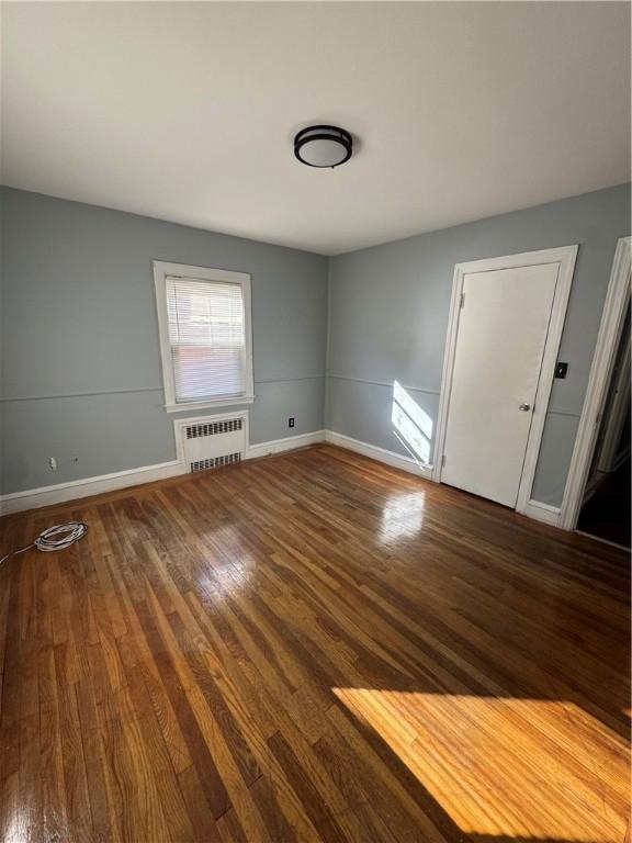 unfurnished room with hardwood / wood-style flooring and radiator