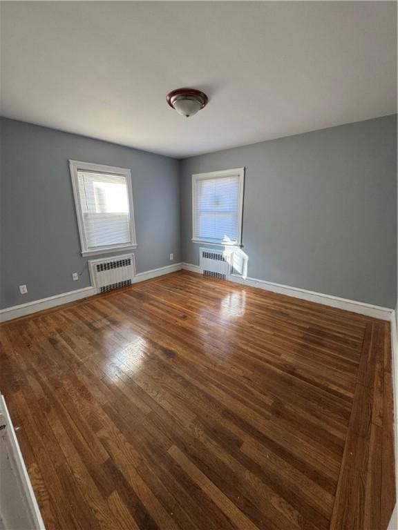 empty room with radiator heating unit and dark hardwood / wood-style floors