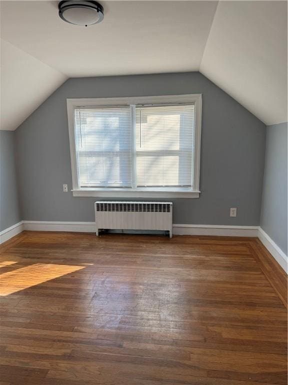 additional living space with lofted ceiling, radiator, and wood-type flooring