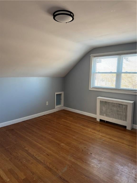 additional living space featuring radiator, vaulted ceiling, and wood-type flooring