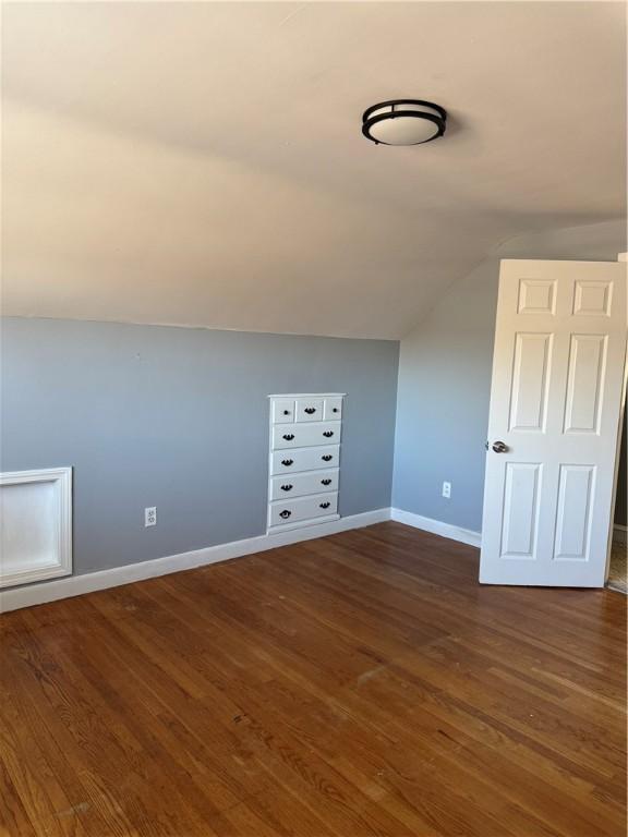 bonus room with dark wood-type flooring and vaulted ceiling