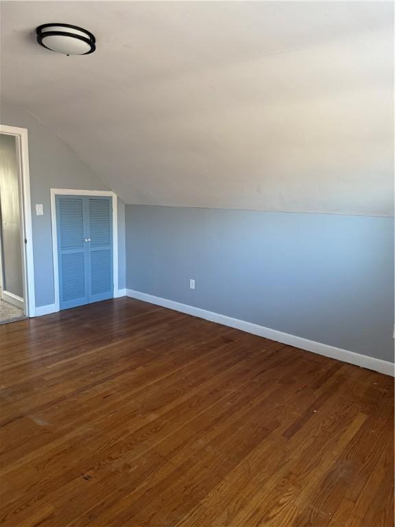 additional living space with dark hardwood / wood-style floors and vaulted ceiling