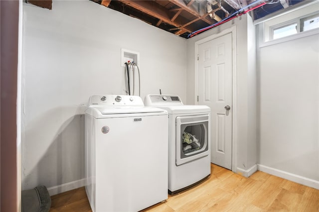 washroom featuring washing machine and dryer and light hardwood / wood-style flooring