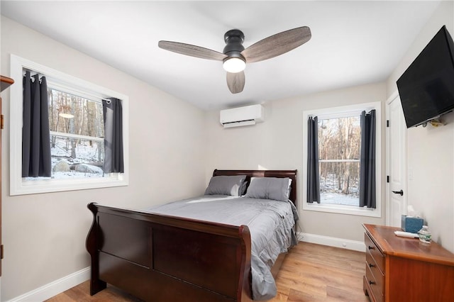 bedroom featuring ceiling fan, light hardwood / wood-style floors, multiple windows, and an AC wall unit