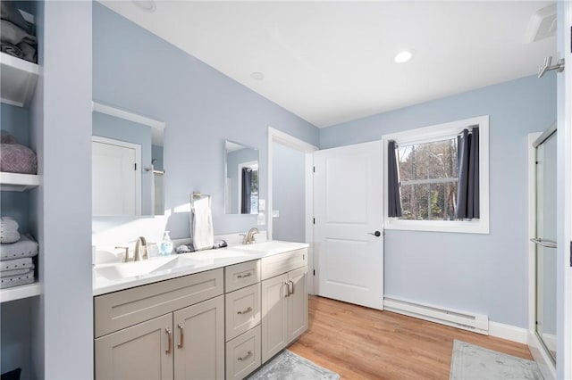 bathroom featuring baseboard heating, wood-type flooring, a shower with shower door, and vanity