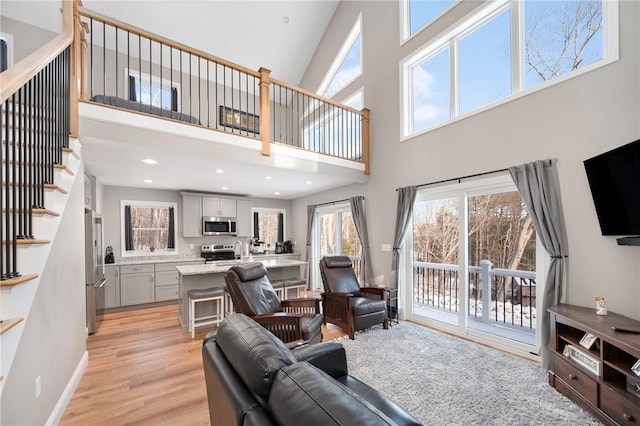 living room featuring light wood-type flooring and a high ceiling