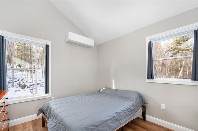 bedroom with lofted ceiling, a wall mounted air conditioner, and wood-type flooring