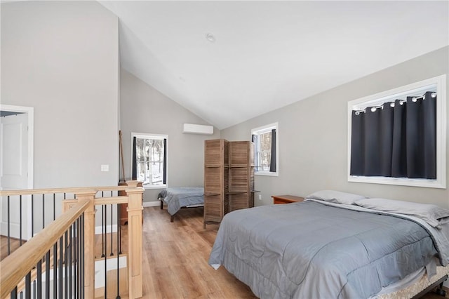 bedroom with lofted ceiling, light hardwood / wood-style floors, and an AC wall unit