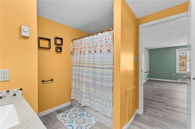 bathroom with vanity, hardwood / wood-style floors, tasteful backsplash, and baseboard heating