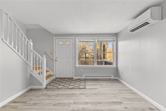 foyer with a wall mounted AC, a textured ceiling, baseboard heating, and light hardwood / wood-style flooring