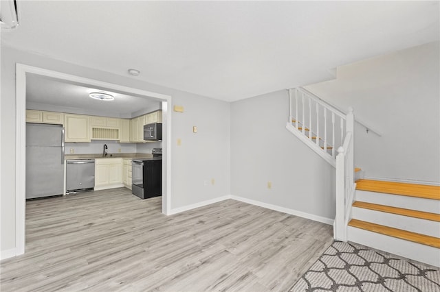 unfurnished living room featuring sink and light hardwood / wood-style flooring