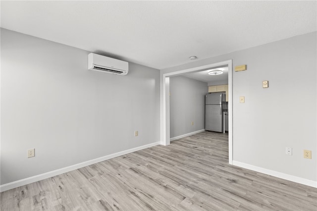 unfurnished room featuring an AC wall unit and light hardwood / wood-style floors