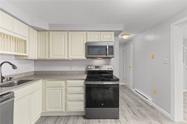 kitchen featuring sink, baseboard heating, stainless steel appliances, cream cabinets, and a textured ceiling