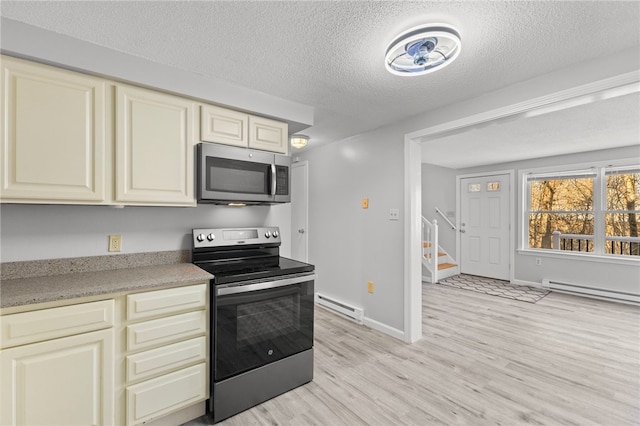 kitchen featuring baseboard heating, appliances with stainless steel finishes, light hardwood / wood-style floors, and cream cabinets