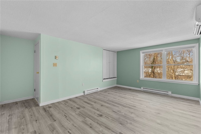 spare room featuring a textured ceiling, light hardwood / wood-style flooring, and a baseboard heating unit