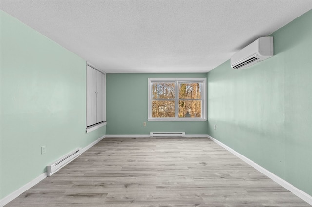 spare room featuring a textured ceiling, a baseboard radiator, light hardwood / wood-style floors, and a wall mounted AC